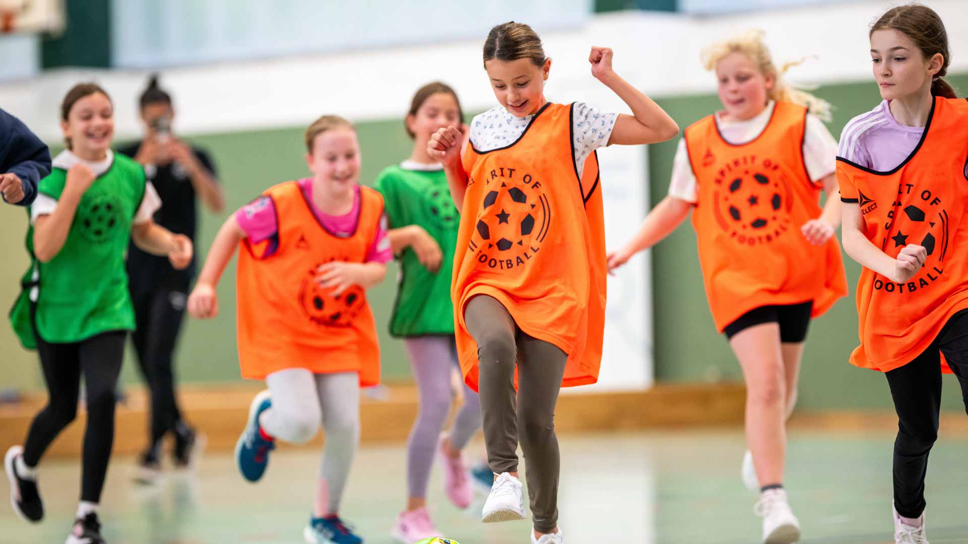 6 Mädchen spielen gemeinsam Fußball und lachen dabei